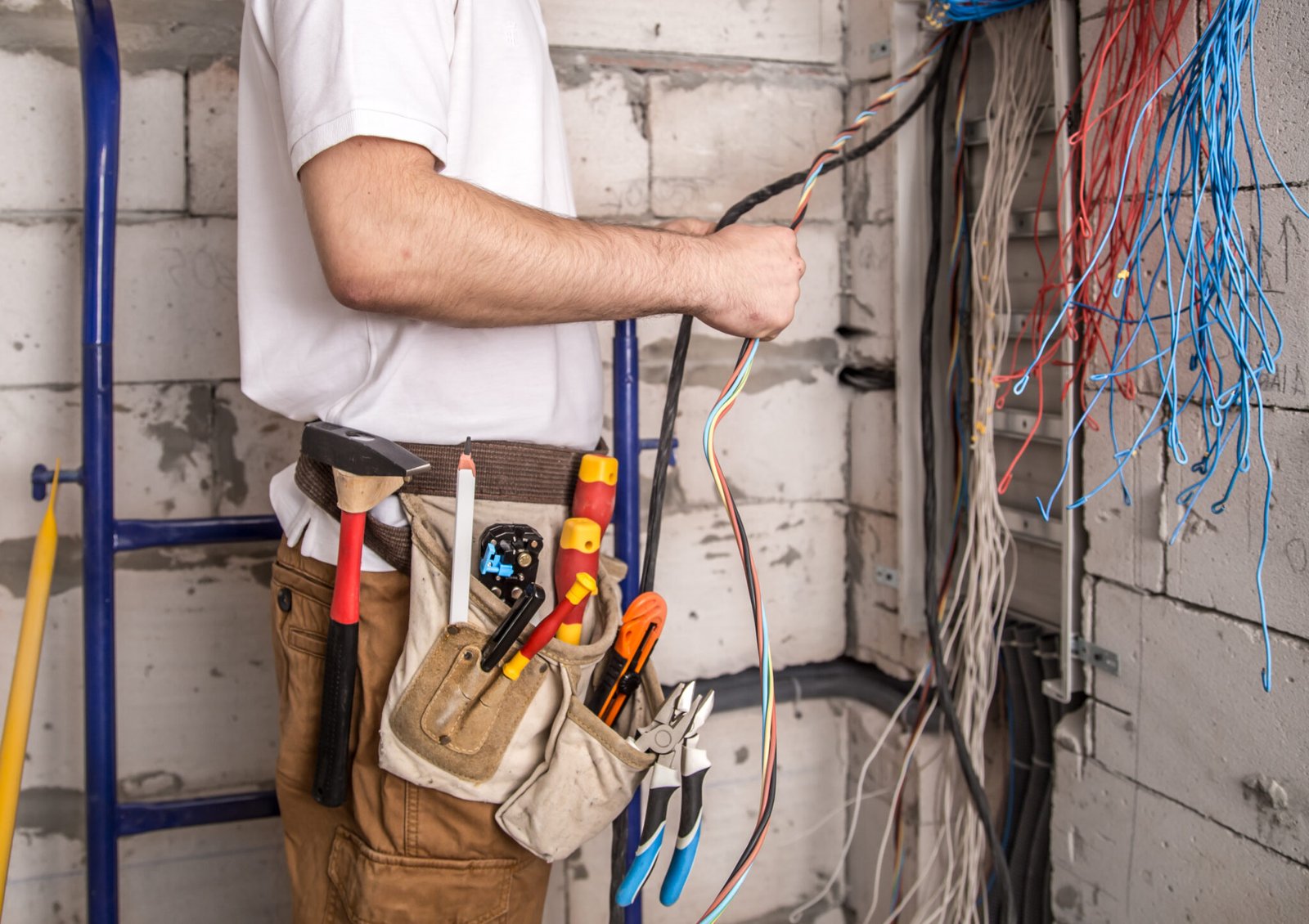 Electrician working near the Board with wires. Installation and connection of electrics. Professional with tools in hand.